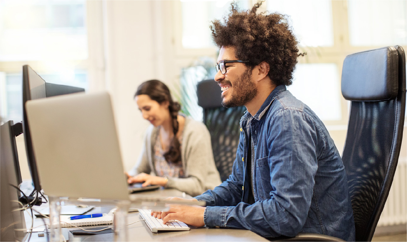 Man at desk on computer smiling
